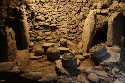 Steingefäße, Platten und Klopfsteine in Fundlage in einem Küchenbereich in Karahantepe (Provinz Şanlıurfa, Türkiye), 9400 – 8000 v. Chr