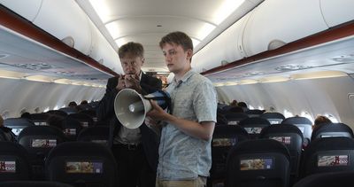 Mux (Jan Henrik Stahlberg) und Karsten (TilmanVellguth) versuchen Flugzeugpassagiere vom Muxismus zu überzeugen