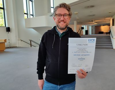 Chorleiter Patrick Jaskolka mit der Siegerurkunde des Wettbewerbs 