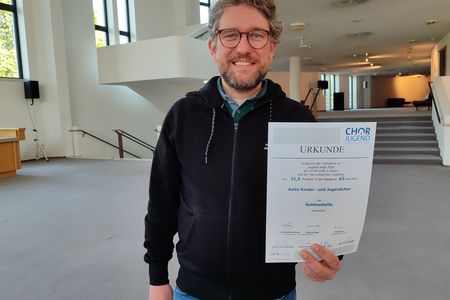 Chorleiter Patrick Jaskolka mit der Siegerurkunde des Wettbewerbs 