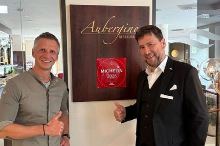 Küchenchef Maximilian Moser und Jean-Marc Ferrara, seit September 2026 Leiter des Gourmetrestaurant Aubergine, mit der frischen Plakette des „Guide MICHELIN