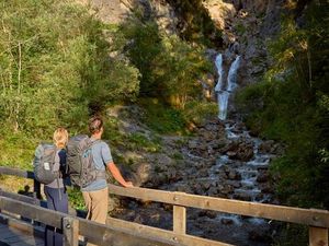 Auf dem Lechweg-Teilabschnitt in Steeg/Tiroler Lechtal kommen Wanderer an der Natur-Kneippanlage Griesbacherwasserfall vorbei Auf dem Lechweg-Teilabschnitt in Steeg/Tiroler Lechtal kommen Wanderer an der Natur-Kneippanlage Griesbacherwasserfall vorbei