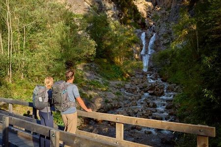 Auf dem Lechweg-Teilabschnitt in Steeg/Tiroler Lechtal kommen Wanderer an der Natur-Kneippanlage Griesbacherwasserfall vorbei