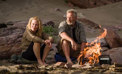Raynor (Gillian Anderson) und Moth Winn (Jason Isaacs) wärmen sich am Feuer