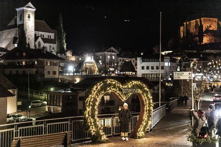 Während Schennas geschmücktes Dorfzentrum zum Verweilen und Eislaufen einlädt, genießen Familien die verschneite Südtiroler Bergwelt beim Rodeln und Schneeschuhwandern