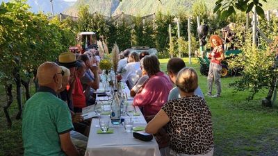 Kulinarischer Abend unter freiem Himmel: Im Hotel Campingpark Steiner in Leifers trinken Gäste Südtiroler Weine mitten im Grünen, begleitet von Live-Musik