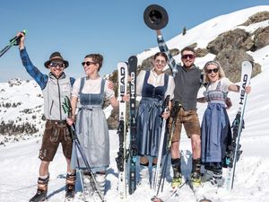 Personen in Tracht und auf Ski stehen gut gelaunt am Pistenrand Personen in Tracht und auf Ski stehen gut gelaunt am Pistenrand