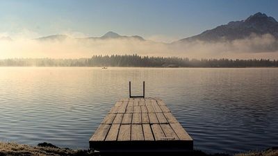 Am Ufer des Hopfensees im bayerischen Füssen genießen gesundheitsbewusste Urlauber die Ruhe und Natur mit Alpenblick