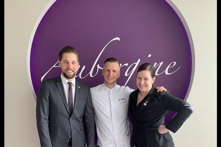 Drei strahlende Gastronomen, zwei Hauben und ein Bild aus Zeiten vor Abstand, Maske und Co. – Restaurantmanager Cornelius Fahl, Kuechenchef Maximilian Moser und Sommelière Claudia Mikschowsky aus dem Gourmetrestaurant Aubergine in Starnberg
