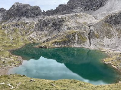 Der Roßkarsee schimmert tiefgruen, umringt wird das Berggewaesser von schroffen Felsformationen der Lechtaler Alpen