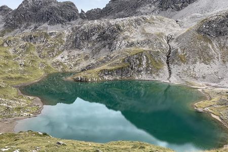 Der Roßkarsee schimmert tiefgruen, umringt wird das Berggewaesser von schroffen Felsformationen der Lechtaler Alpen