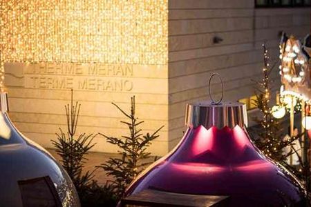 Beim Dinner in den „Kugln“ auf dem Platz vor der Therme Meran speisen Gäste inmitten des Weihnachtsmarkt-Trubels der Südtiroler Kurstadt