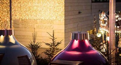 Beim Dinner in den „Kugln“ auf dem Platz vor der Therme Meran speisen Gäste inmitten des Weihnachtsmarkt-Trubels der Südtiroler Kurstadt