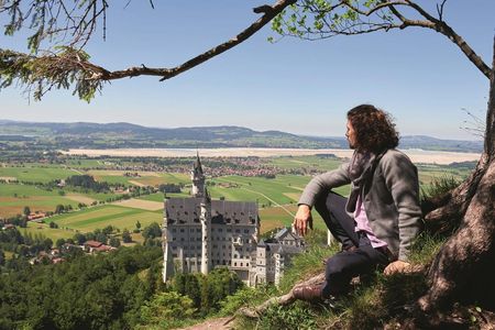Schauspieler Jakob Graf, einer der Protagonisten der Anderszeit-Stories auf der Füssen-Website, mit Schloss Neuschwanstein/Allgäu im Hintergrund
