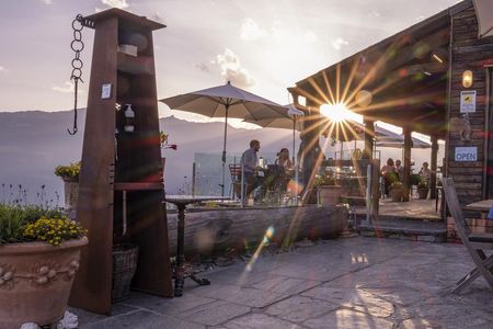 Saluti dal Ticino – im Außenbereich des auf 1.400 Metern gelegenen Ristoro Sass Malt im Südschweizer Malvaglia greifen Gäste beim Sonnenuntergang nach dem Glas und manchmal sogar zu den Sternen