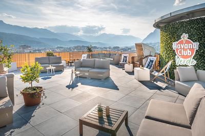 Im 13. Stock des ADLERS Lifestyle-Hotel Innsbruck/Tirol entspannen Besucher bei Rum‑Drinks in der Havana Bar