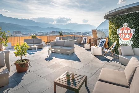 Im 13. Stock des ADLERS Lifestyle-Hotel Innsbruck/Tirol entspannen Besucher bei Rum‑Drinks in der Havana Bar