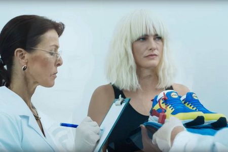 Mit Atomic Blonde Peruecke und bunten Lidl Sneakern wird die Geheimagentin zur LidlMitarbeiterin
