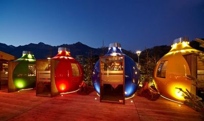 Beim Dinner in einer der Kugln auf dem Platz vor der Therme Meran speisen Gäste entspannt inmitten des Weihnachtsmarkt-Trubels der Südtiroler Kurstadt