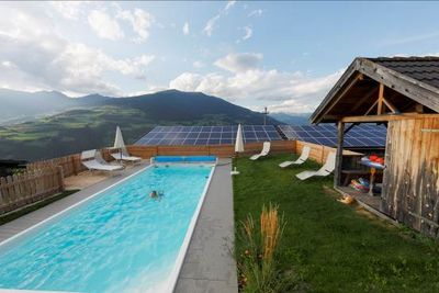 Pool mit Bergblick auf einem der hoch gelegenen Suedtiroler Bauernhoefe der Marke Roter Hahn