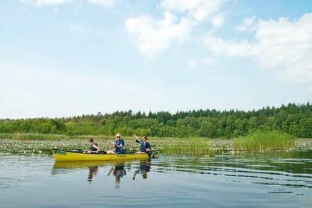 Beim Anpaddeln erkunden aktive Urlauber die abwechslungsreiche und unberuehrte Natur der Mecklenburgischen Seenplatte vom Kanu aus