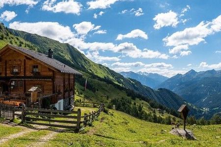 Eine Almhütte, ein Marterl, unberührte Natur und Berge, soweit das Auge reicht