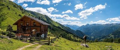 Eine Almhütte, ein Marterl, unberührte Natur und Berge, soweit das Auge reicht