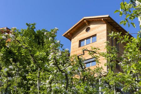 Inmitten von Apfelbäumen ist das Gästehaus des Greiterhofs in Lana ein echter Blickfang. Unter anderem aufgrund seiner Massivholzbauweise erfüllt es die Anforderungen für einen 4-Blumen-Hof der Südtiroler Qualitätsmarke „Roter Hahn“