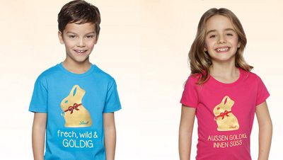 Merchandsing T-Shirts, die Lindt für Jungen und Maedchen anbietet. Bei den Jungs steht auf gruenem Untergrund: Frech, wild, goldig. Die Maedchen werden mit Außen goldig, innen sueß bezeichnet