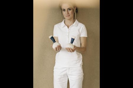 Julia Kraler, Spa-Leiterin des Naturhotel Leitlhof in Suedtirol mit zwei Stoffstempeln, die mit Kraeutern gefuellt und erwaermt die Haut reinigen